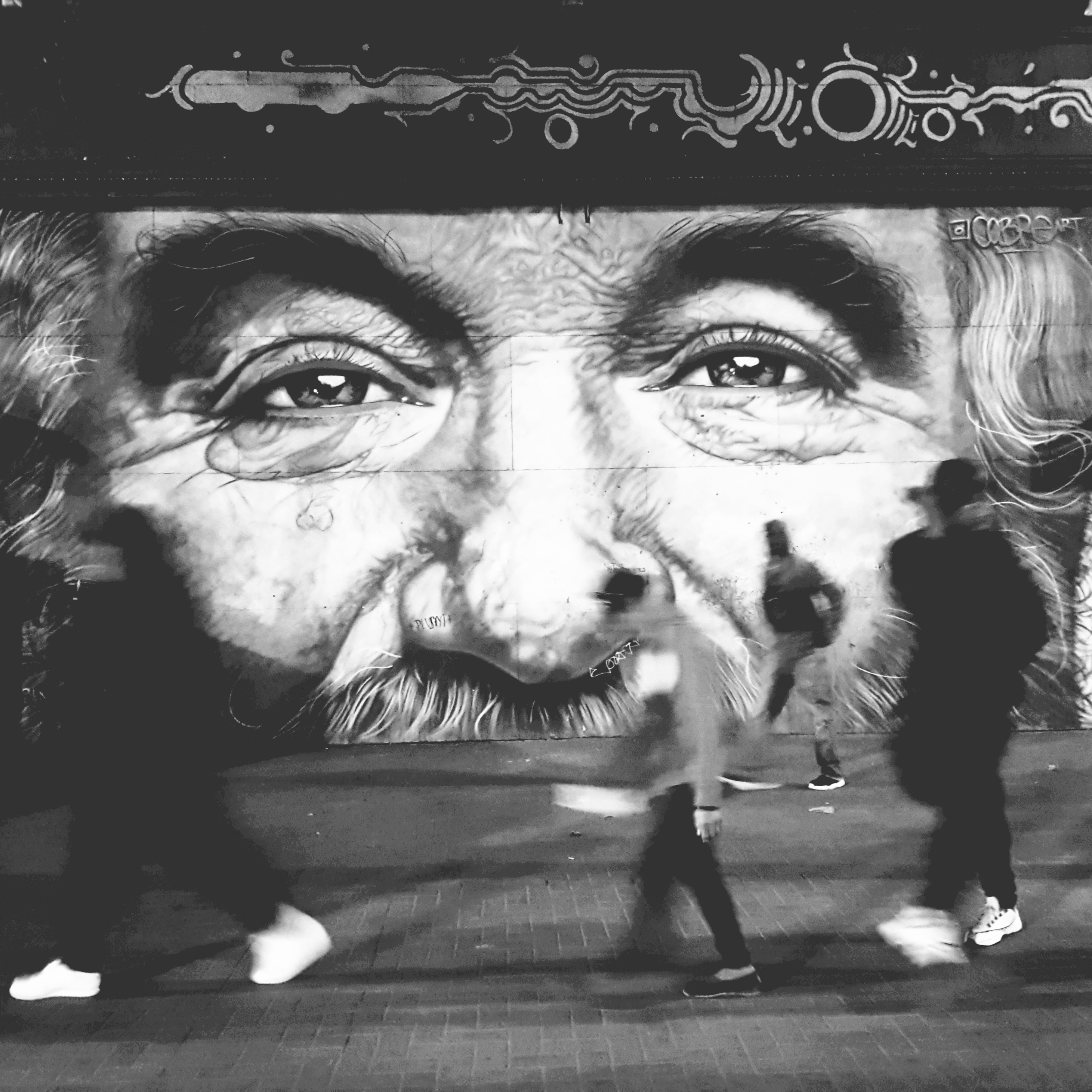 Black and white street mural with people walking in front