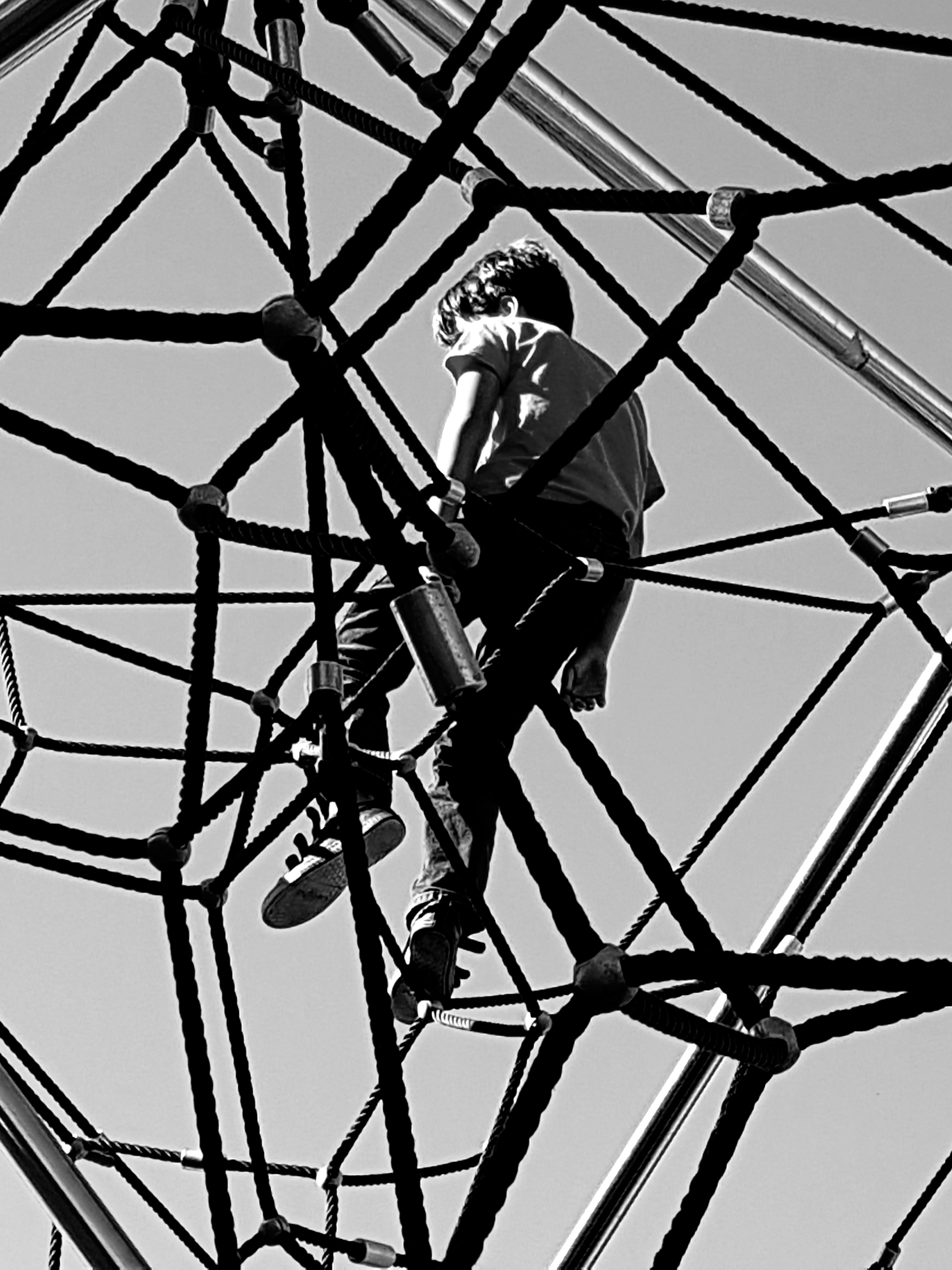 Person climbing through a rope structure seen from below